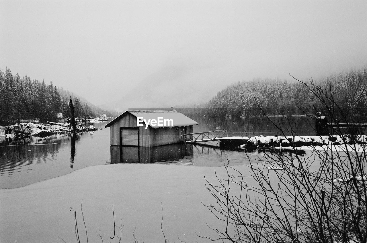 House by lake against clear sky during winter