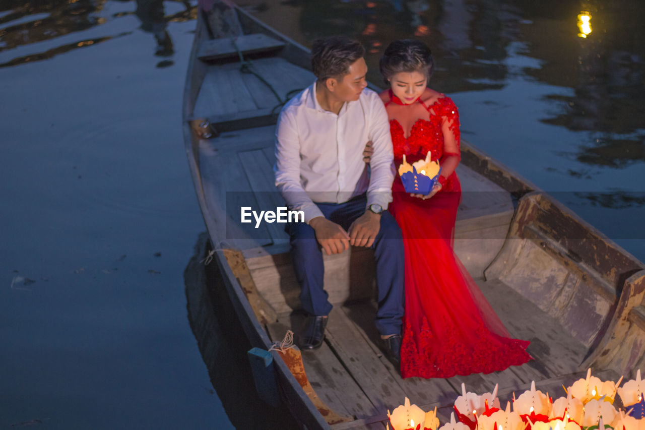 COUPLE HOLDING A BOAT IN WATER AT THE SEA