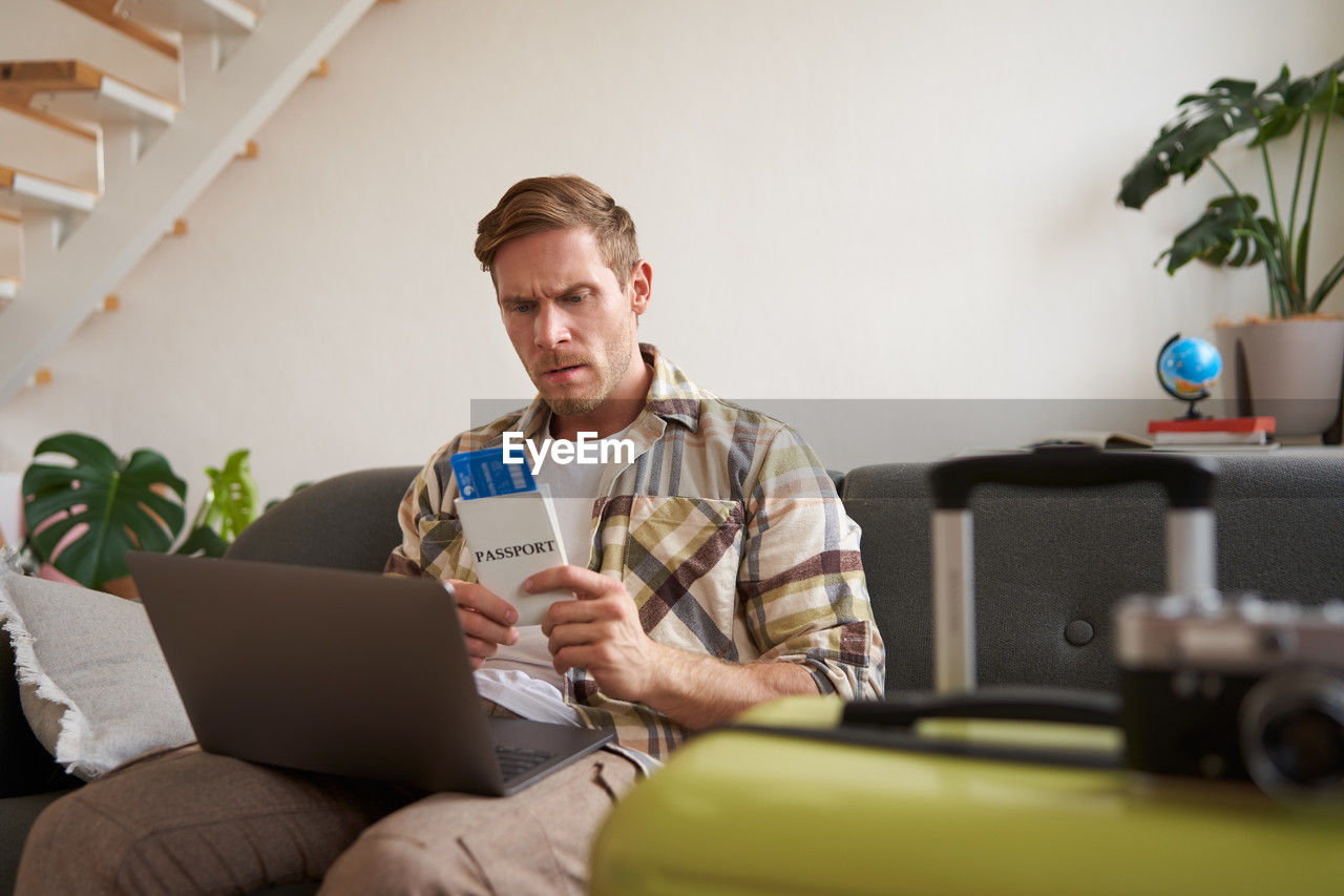 young woman using mobile phone while sitting on sofa at home