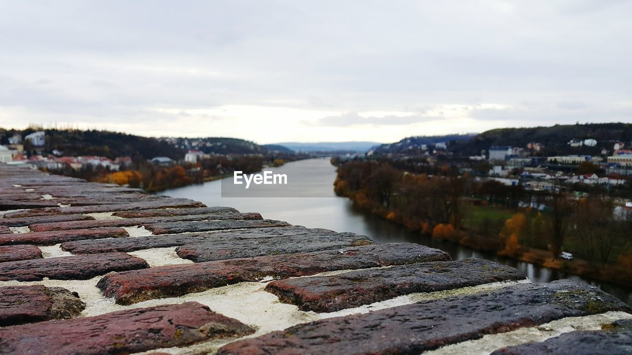 Retaining wall by river against sky