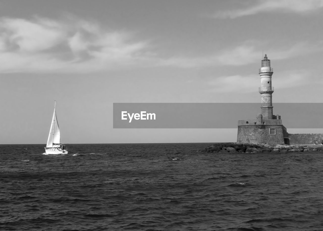 SAILBOAT SAILING ON SEA BY BUILDINGS AGAINST SKY