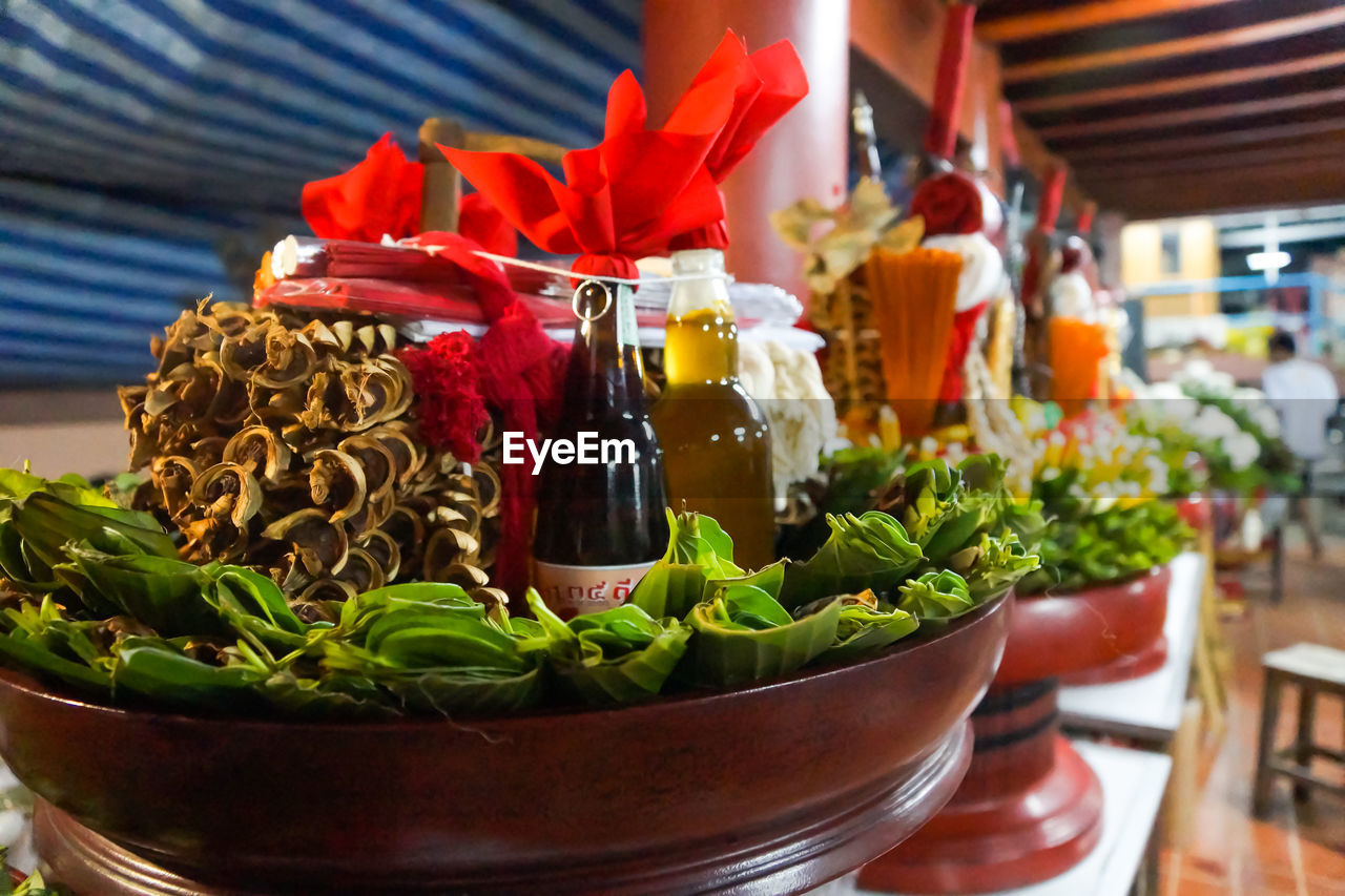 Oil in bottles with betel leaves in container on table at market