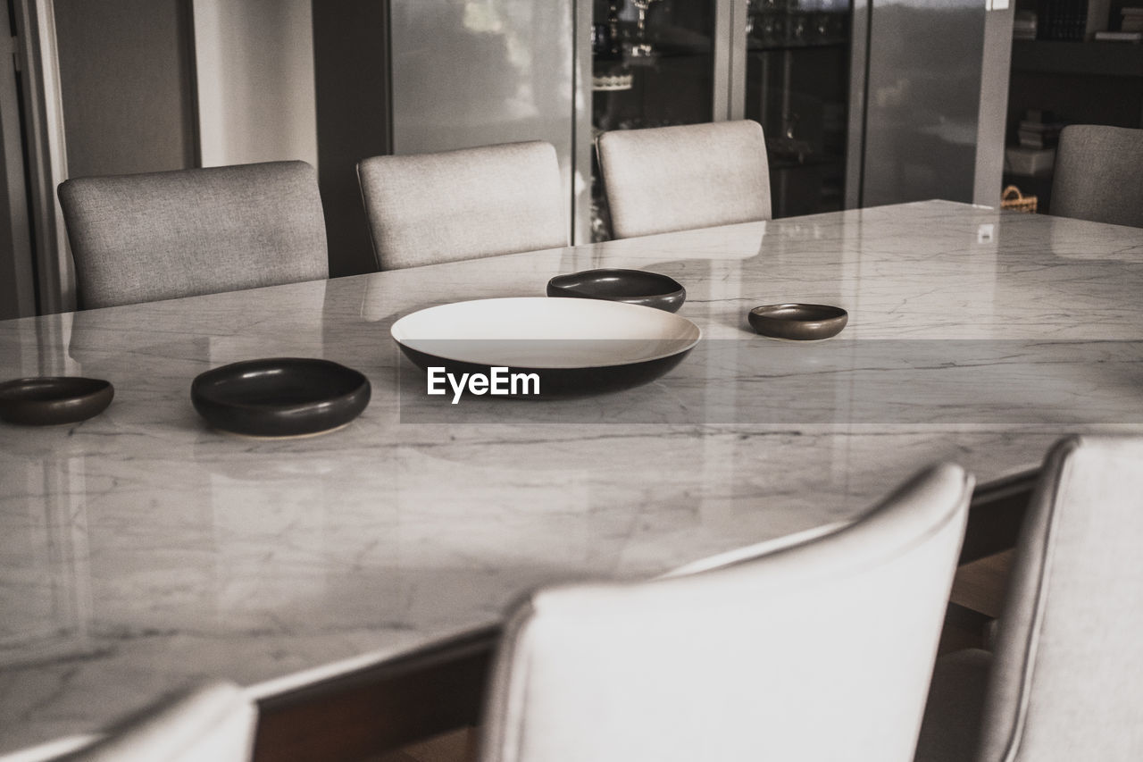 room, white, table, indoors, black, floor, furniture, seat, flooring, black and white, no people, home interior, interior design, domestic room, household equipment, home, food and drink, chair, monochrome, sink, monochrome photography, absence, tableware, bowl, wood, home showcase interior, kitchen utensil, countertop