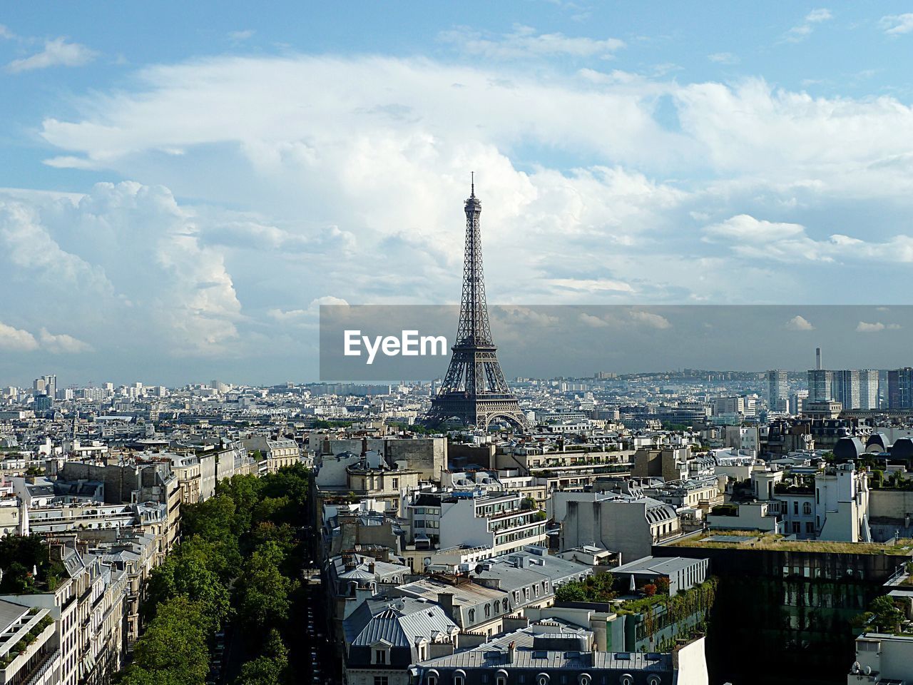 Mid distance of eiffel tower amidst residential district against cloudy sky