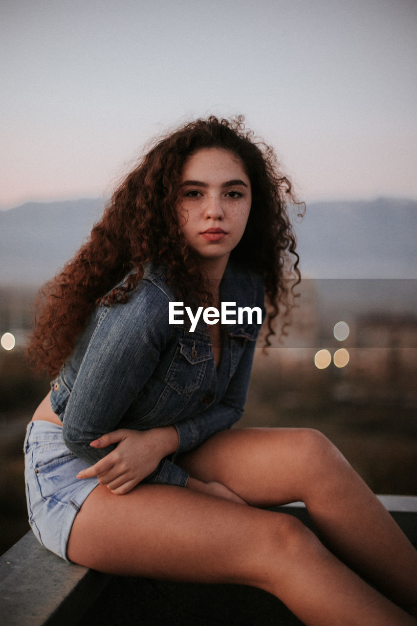 Portrait of young woman sitting outdoors during sunset