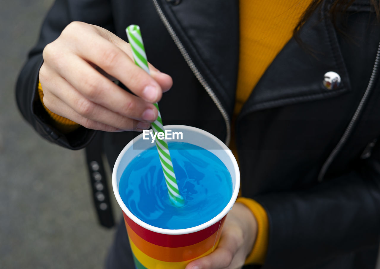 Mixing a blue cocktail with a colorful straw.