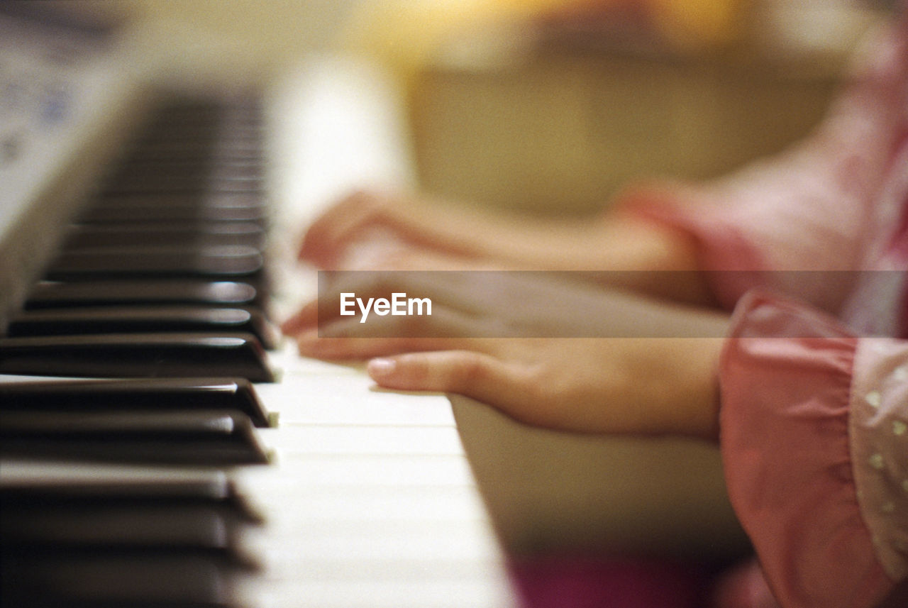 CLOSE-UP OF HANDS PLAYING PIANO AT HOME