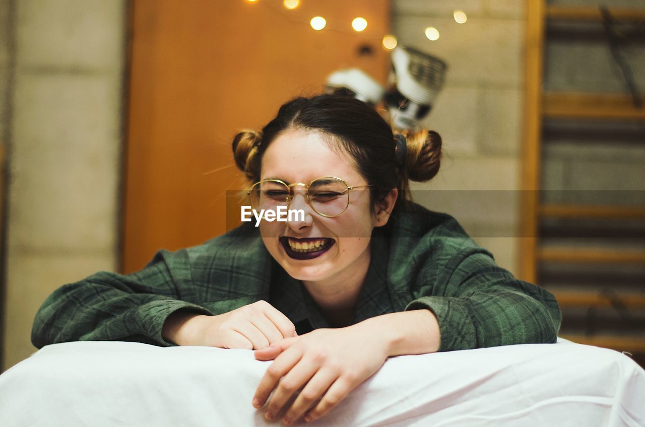 Close-up of happy young woman lying on bed at home