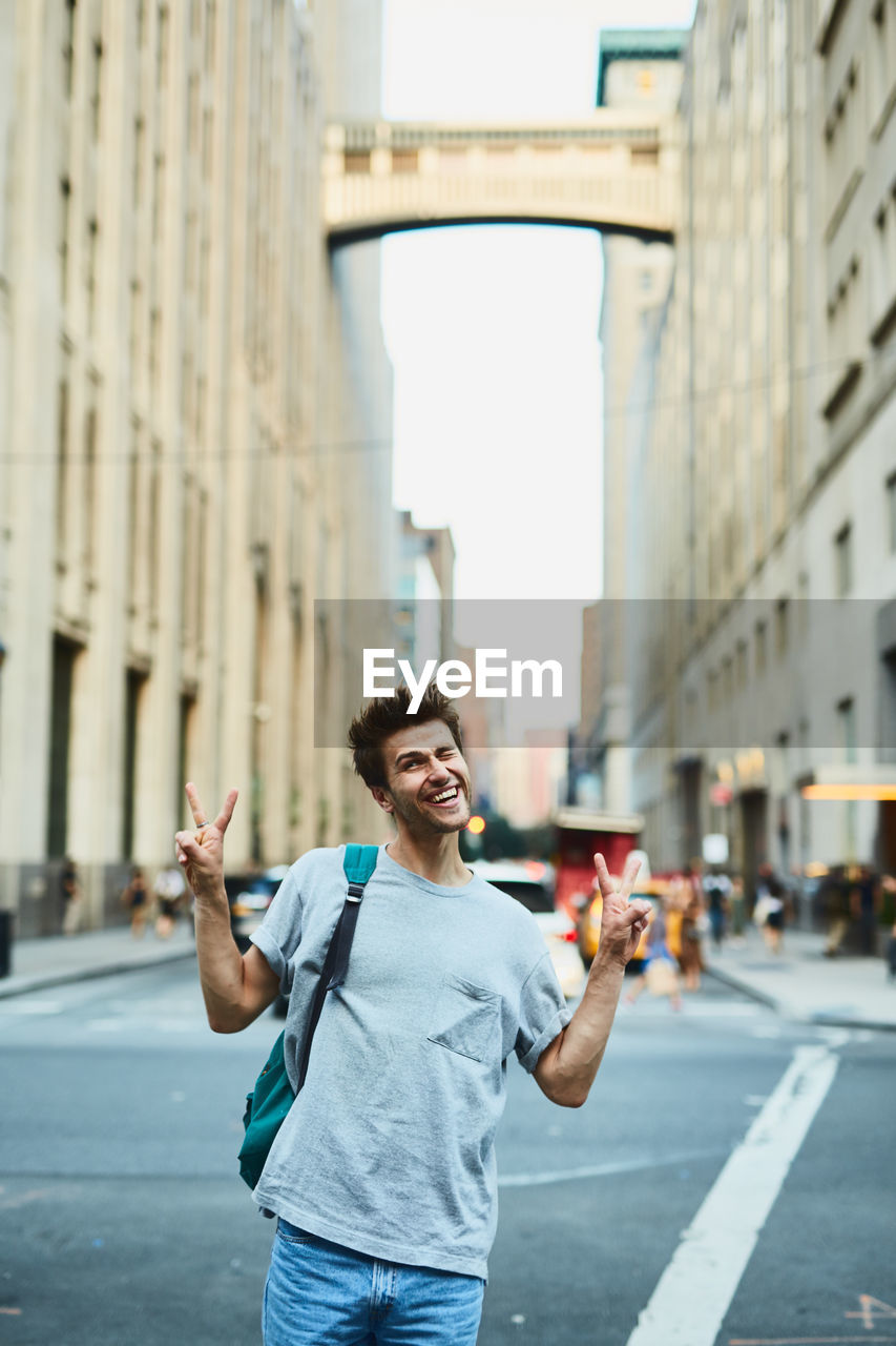 Young man gesturing peace sign while standing in city