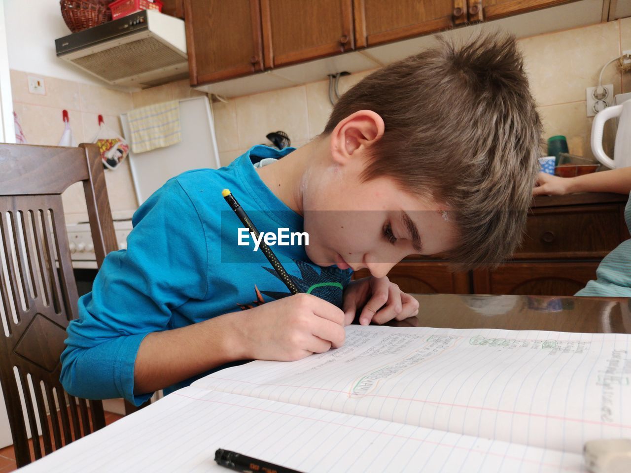 Cute boy writing in book at home