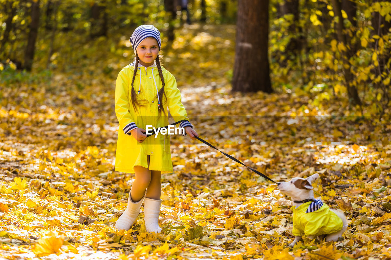 FULL LENGTH OF GIRL WITH YELLOW UMBRELLA IN FOREST