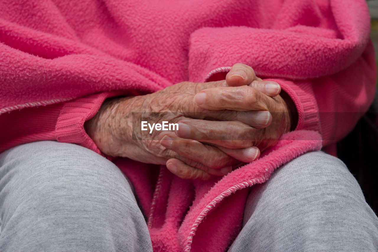 Hands of a old woman with pink blanket