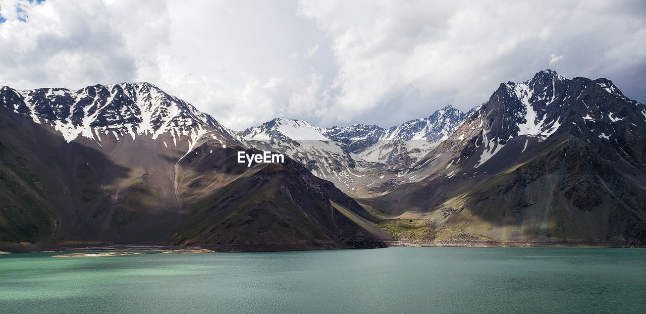 Scenic view of snowcapped mountains and a beautiful lake. cajon del maipo, chile.