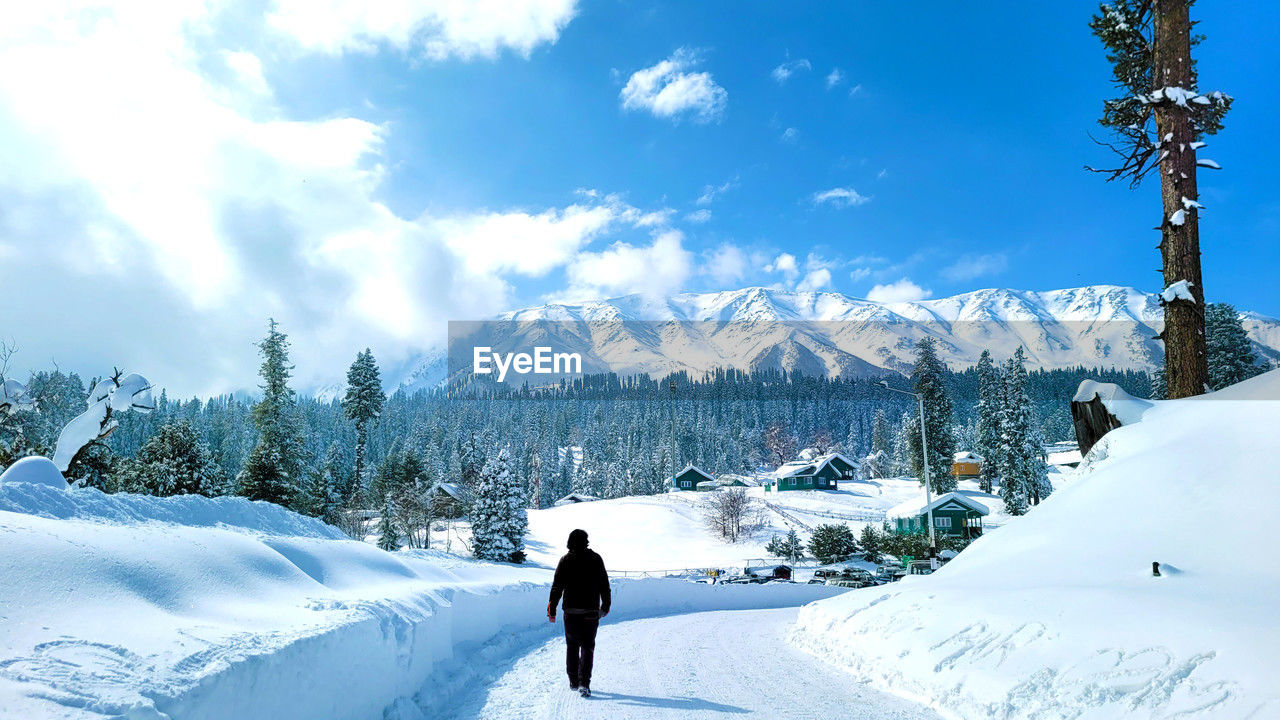 rear view of man walking on snow covered landscape