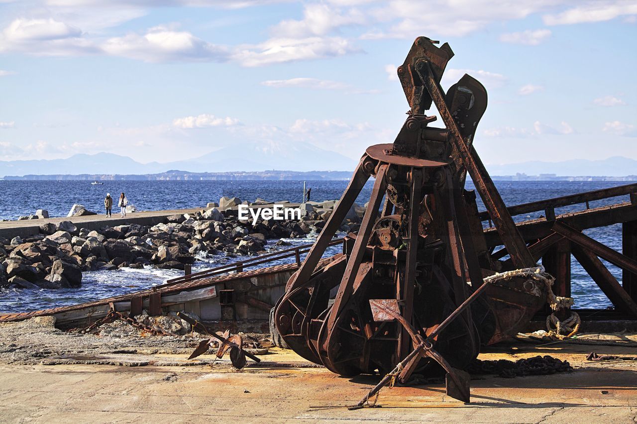 View of damaged machinery on beach against sky