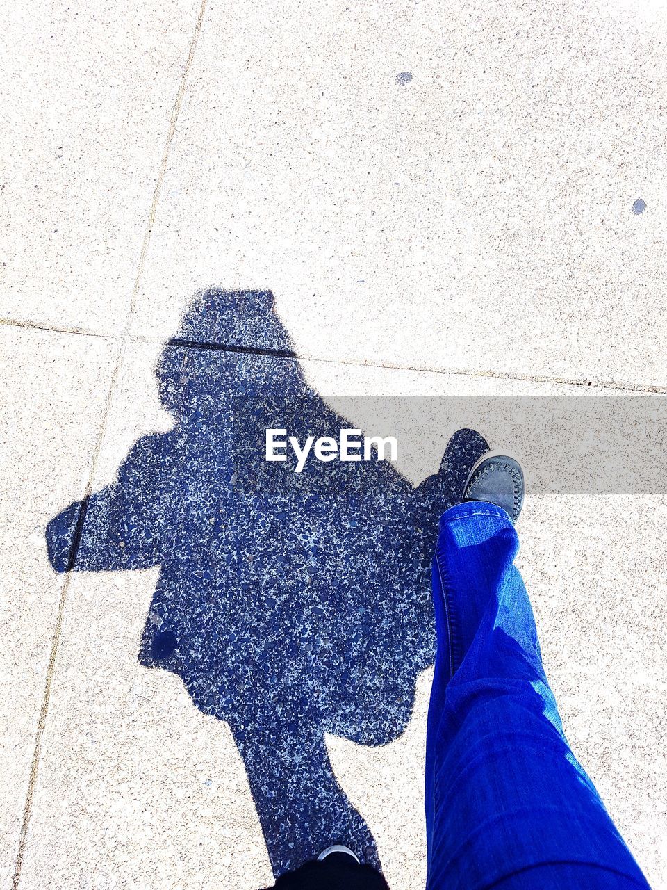 LOW SECTION OF MAN STANDING ON SHADOW OF FOOTPATH