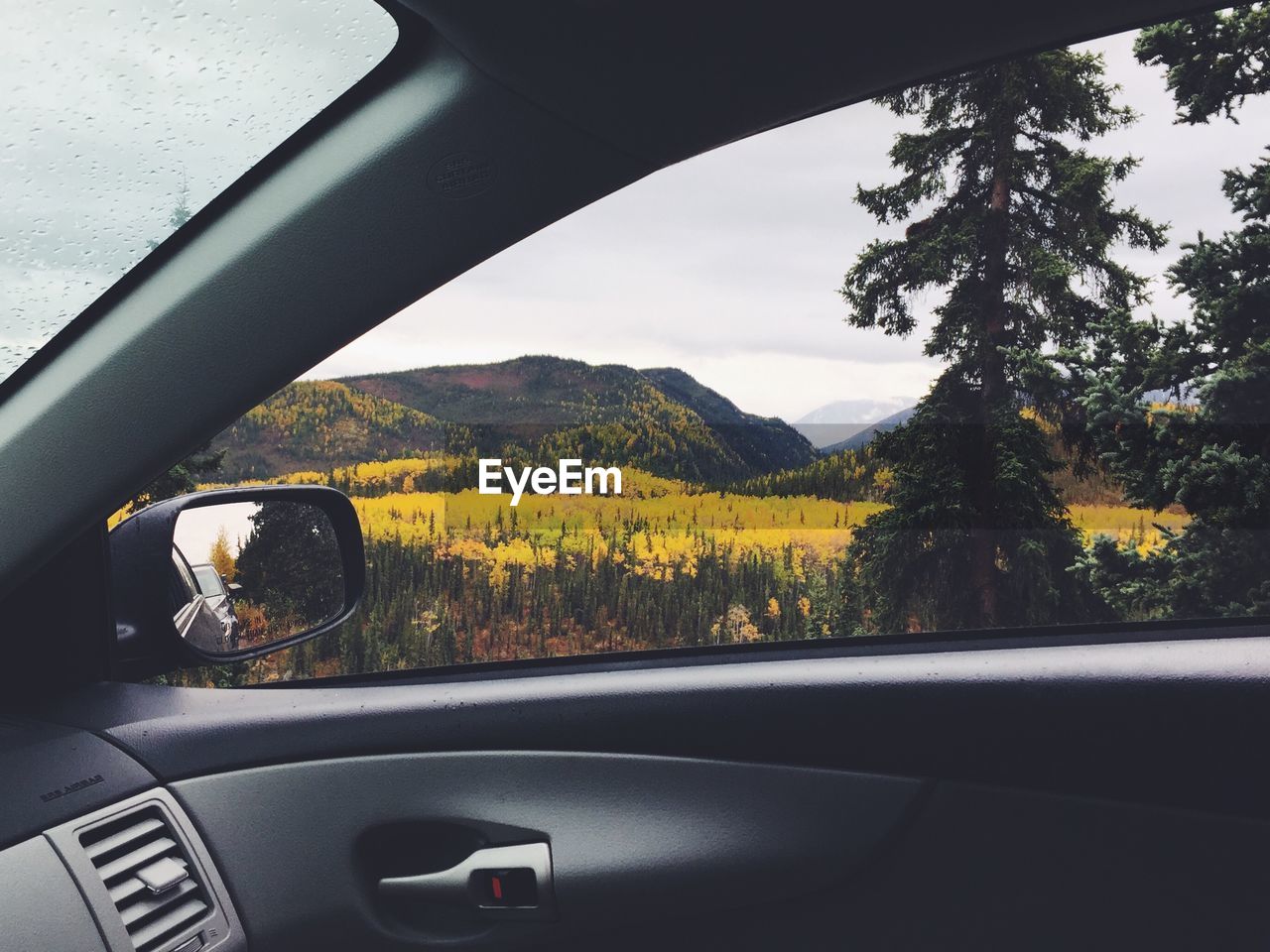 Scenic view of field by mountains seen from car window