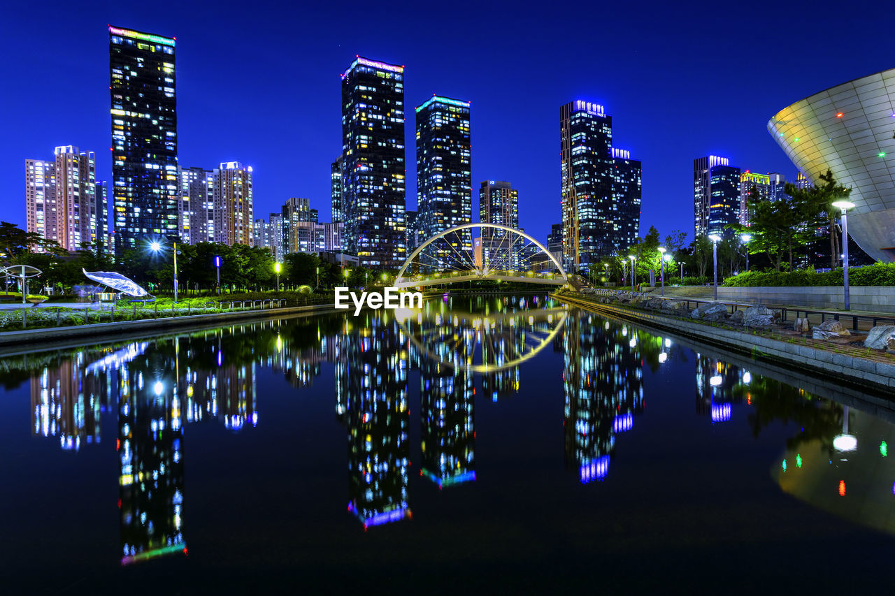 Reflection of illuminated buildings in river against sky