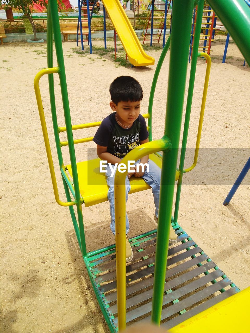 
boy sitting on outdoor play equipment at playground