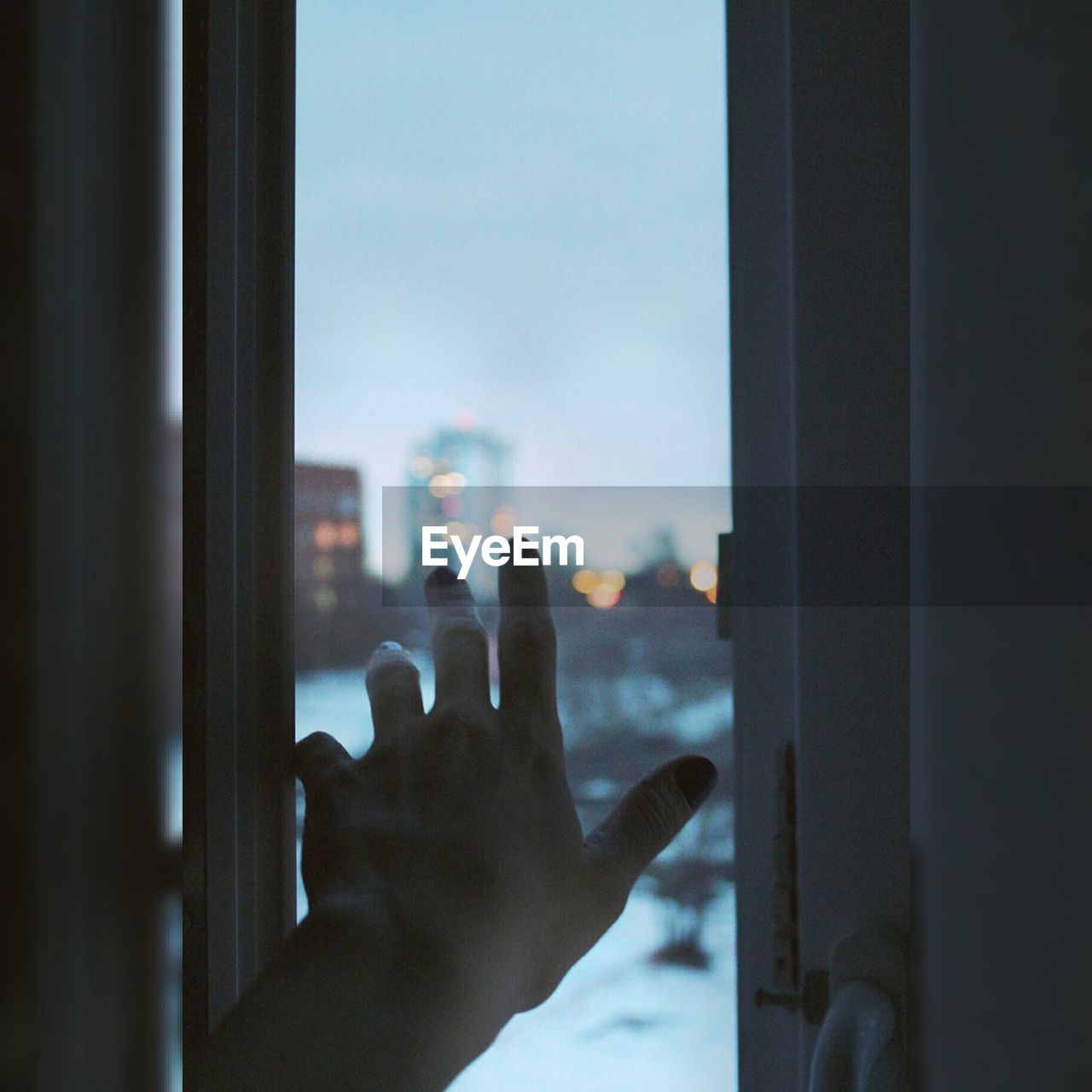Close-up of hand reaching towards window at home