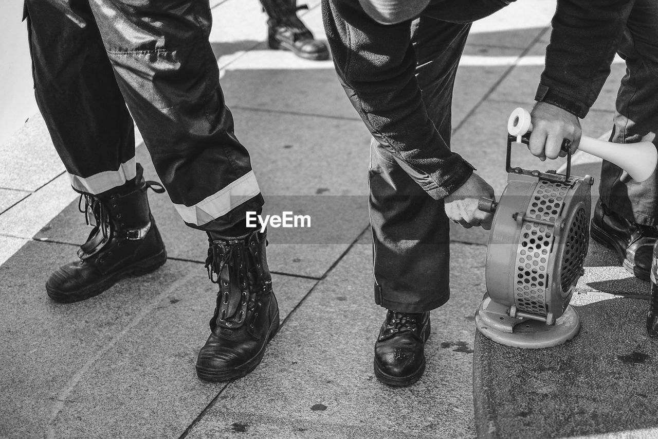 Low section of people in uniform with machinery standing on footpath in city