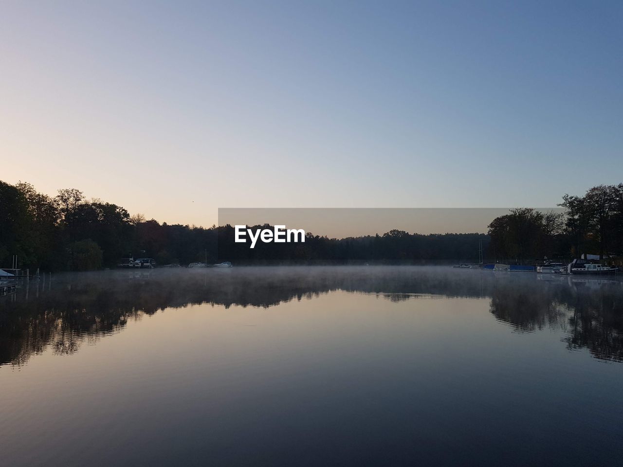 Scenic view of lake against clear sky during sunset