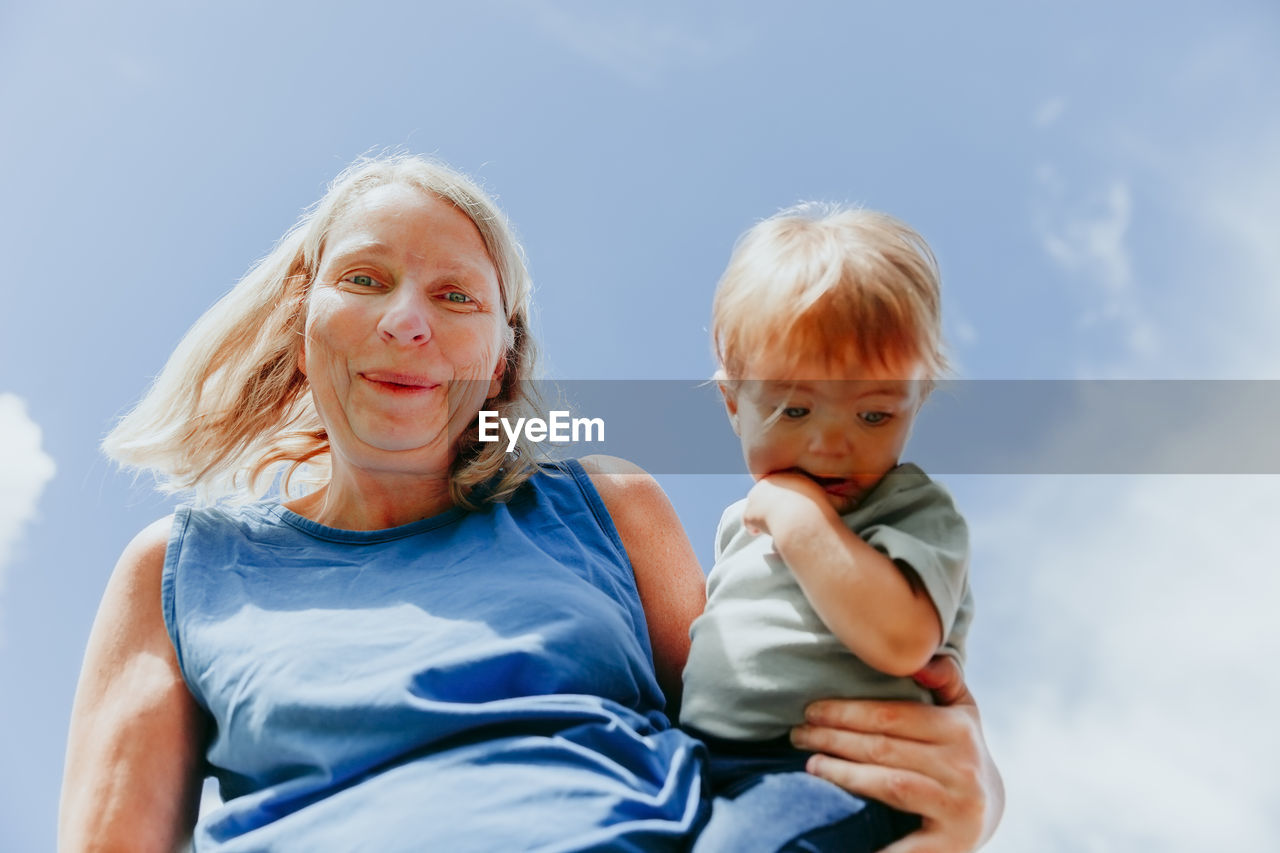 Portrait of woman with son standing against sky