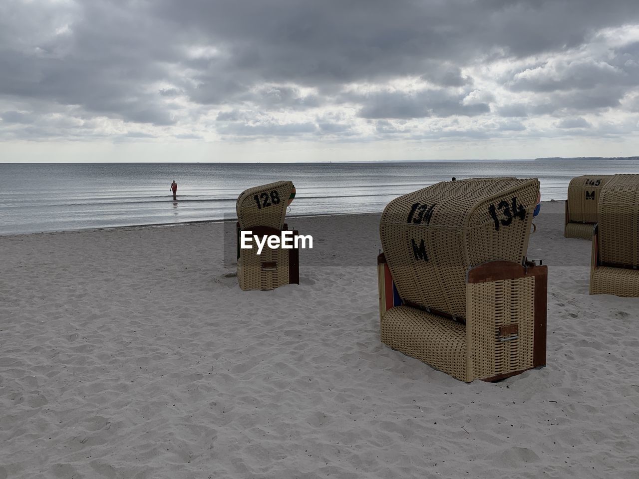 HOODED BEACH CHAIRS ON SAND AGAINST SEA