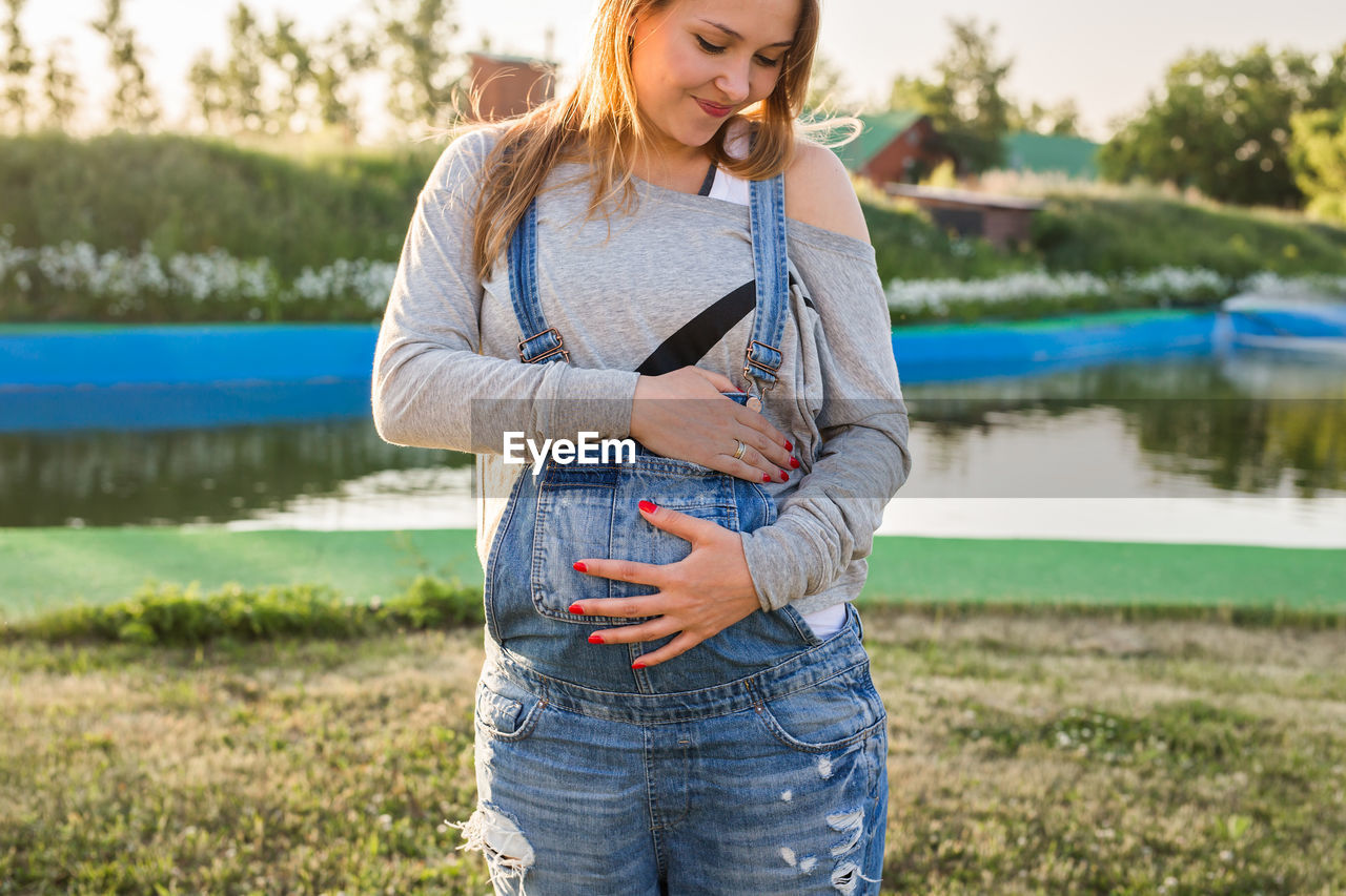 Pregnant woman standing by lake