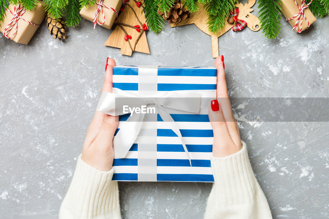 Top view of a woman holding a gift box in her hands. fir tree and christmas decorations. new year.