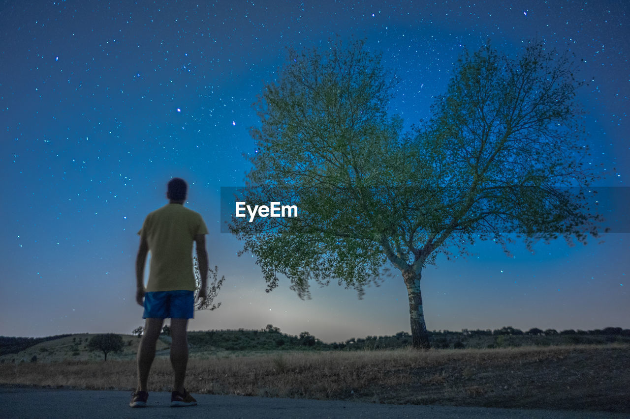 Rear view of man standing on field against sky