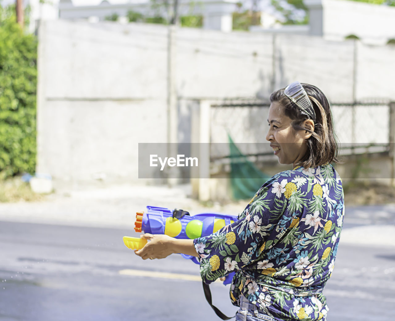 Young woman playing with squirt gun on road