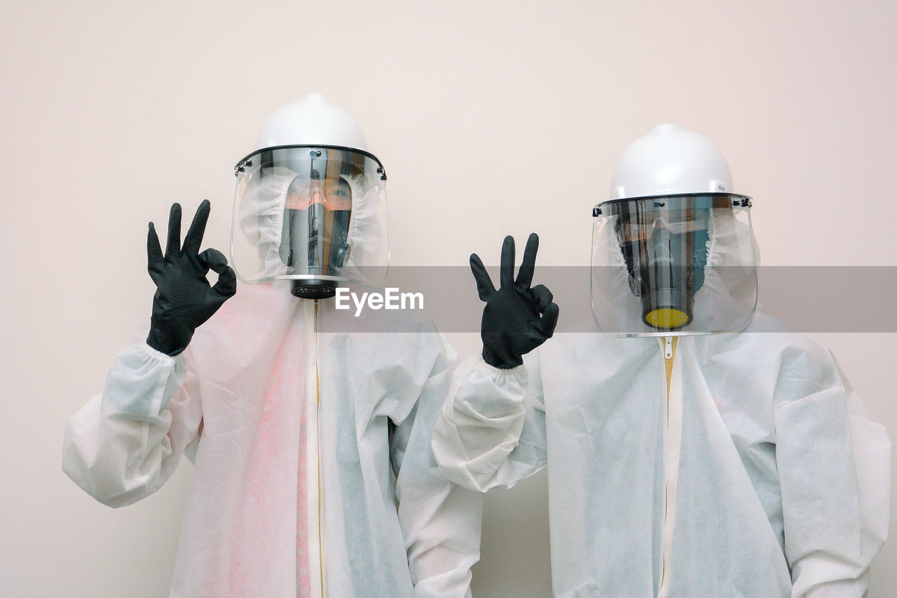 Portrait of doctor wearing protective suits standing against white background