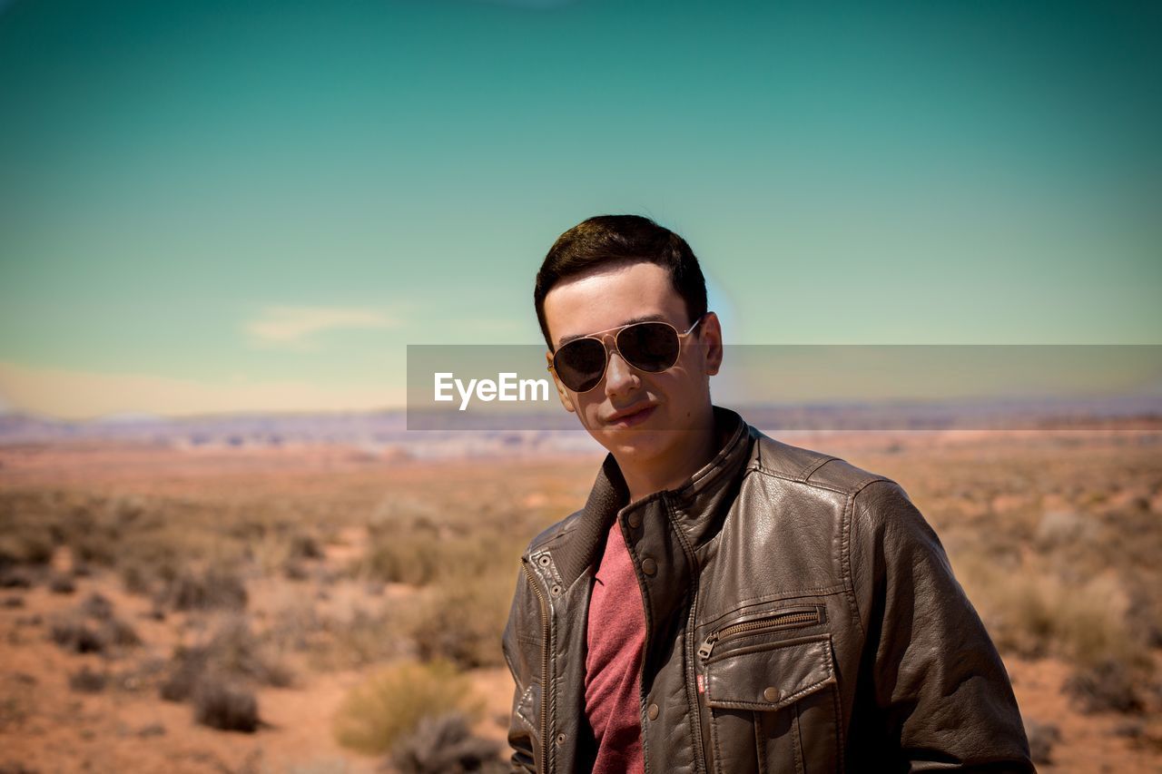 Portrait of man wearing sunglasses while standing against sky during sunset