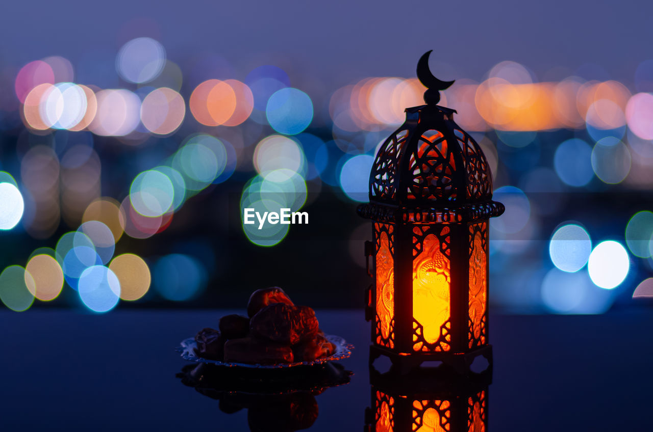 Lantern has moon symbol on top and small plate of dates fruit for holy month of ramadan kareem.