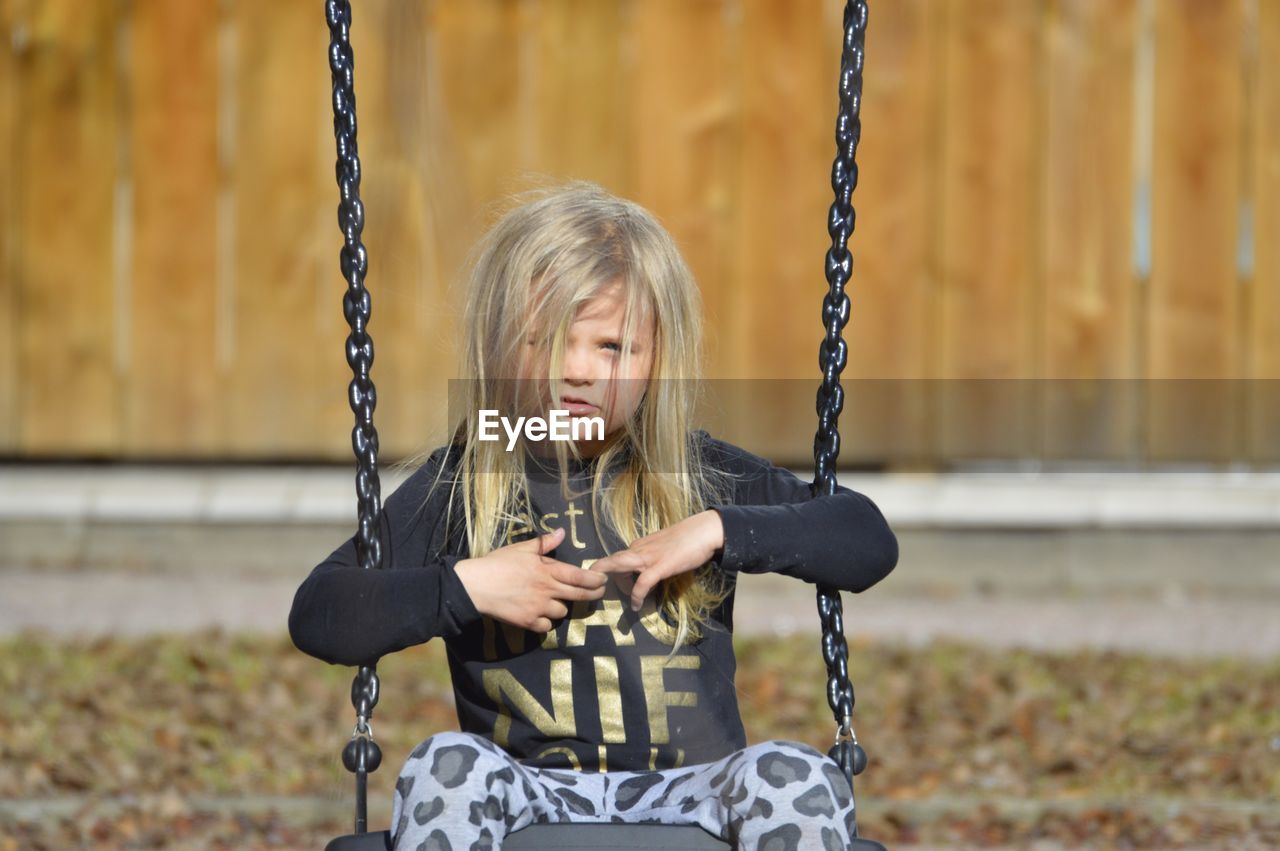 Portrait of cute girl sitting on swing in playground