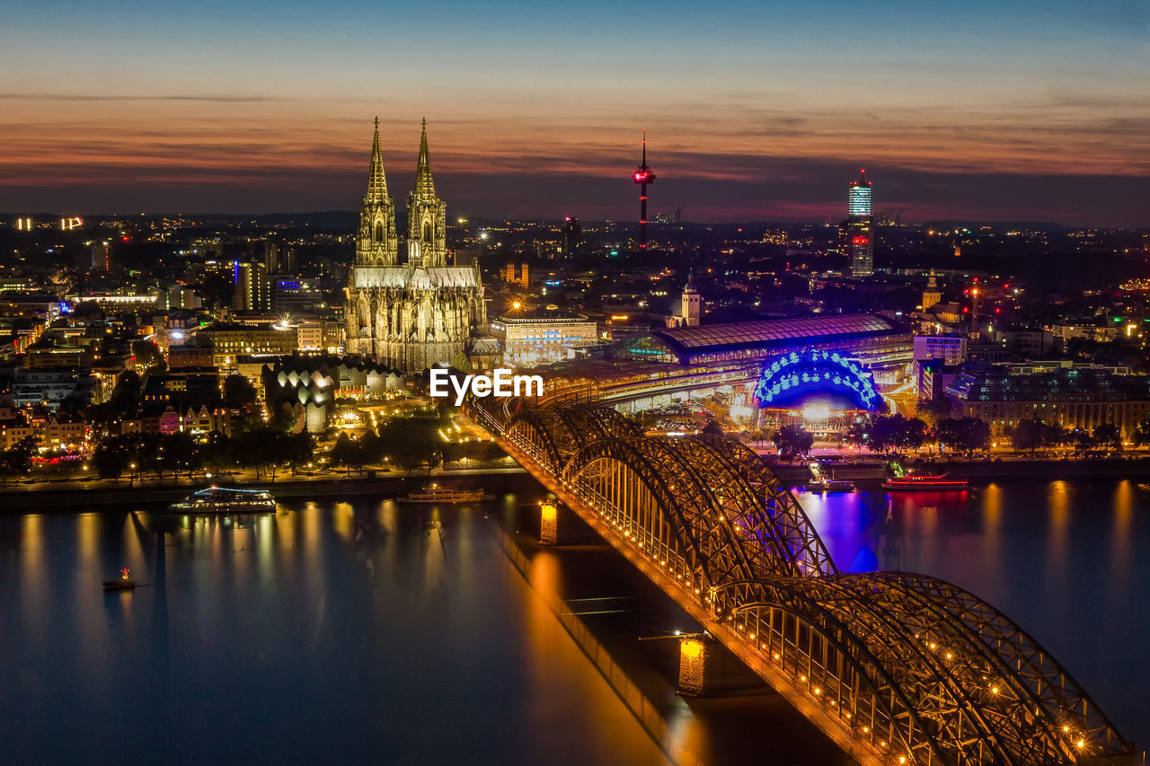 Aerial view of illuminated bridge over river in city at night