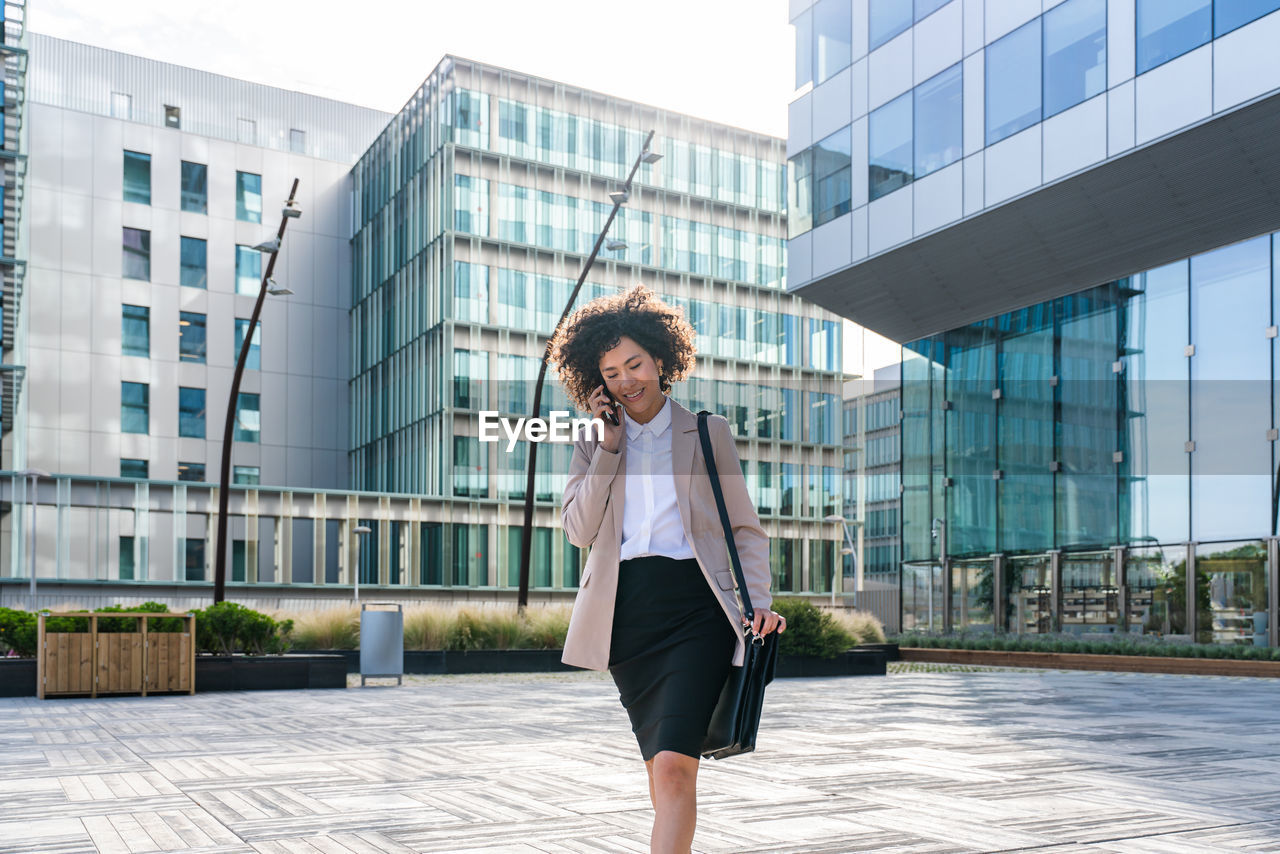 portrait of young woman standing against buildings in city