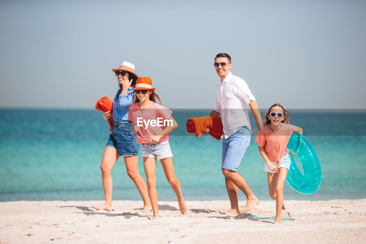 Full length of friends enjoying at beach against sky