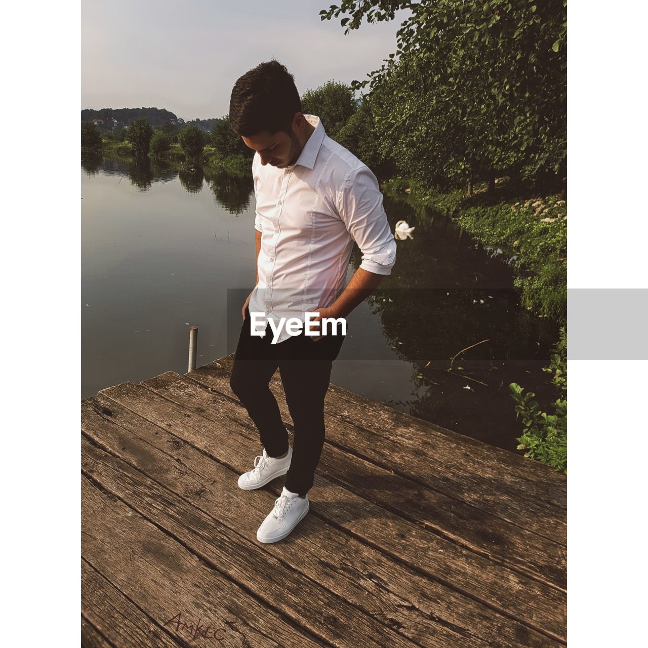 Teenage boy standing on pier over lake