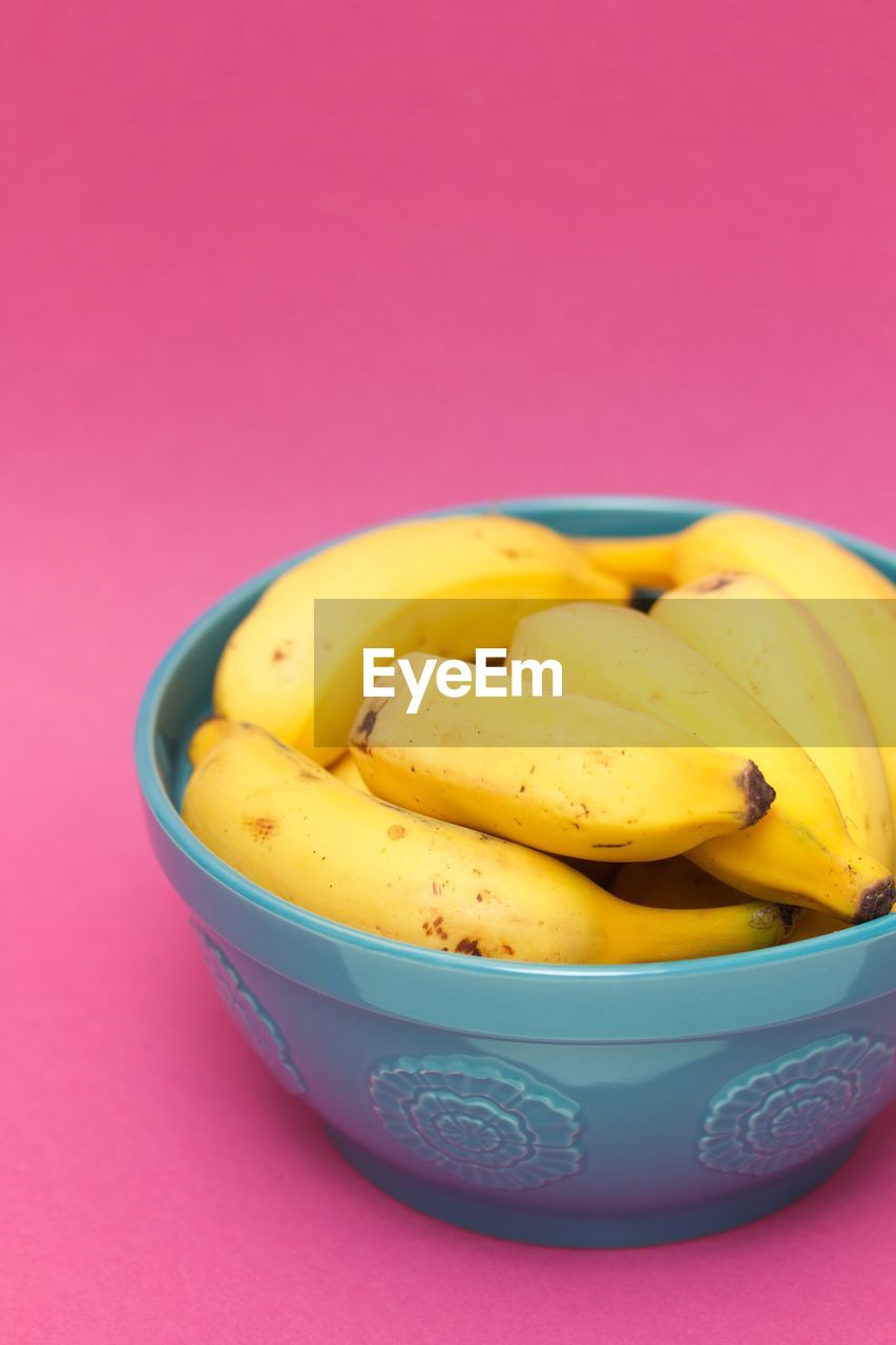 Bananas in a blue bowl on pink background