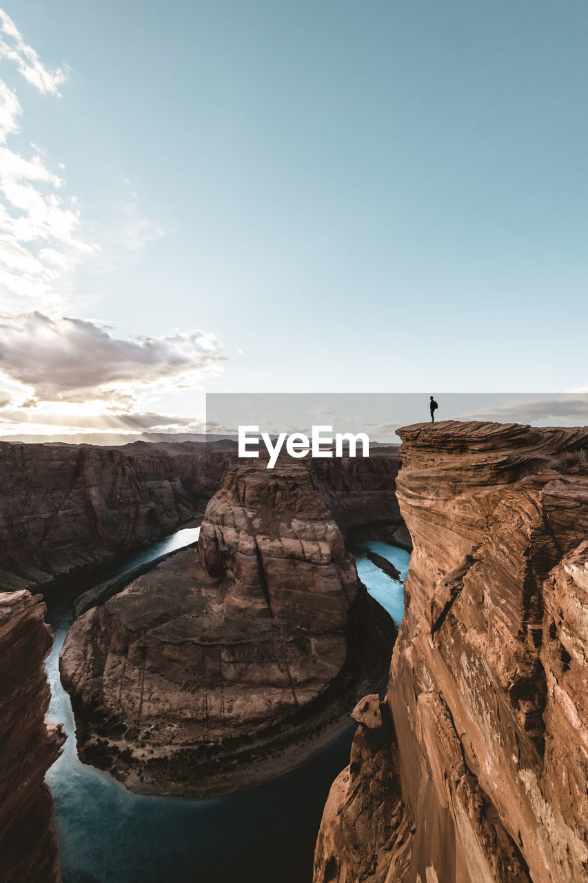 Man standing on rock formations against sky