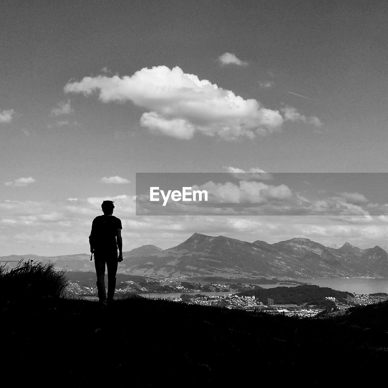 Rear view of man watching mountains against sky