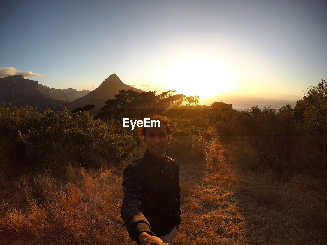 Portrait of man standing on field against sky during sunset