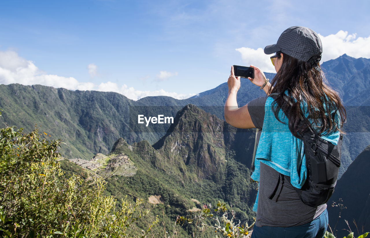 Woman takes a picture on smartphone of machu picchu on the inca trail