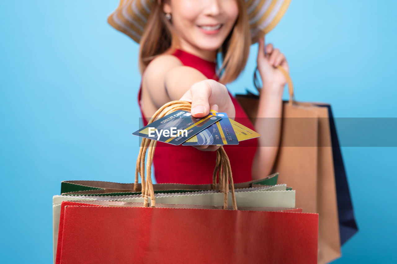 CLOSE-UP OF WOMAN HOLDING RED AND BLUE BACKGROUND