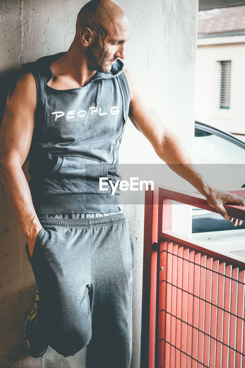 Muscular man leaning on wall in parking lot