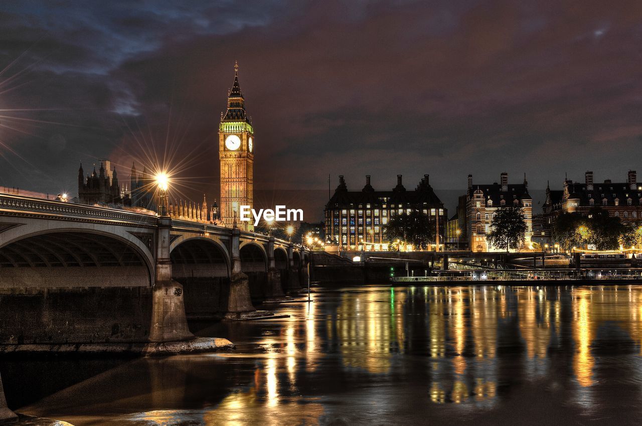 Illuminated bridge over thames river with big ben in city at night