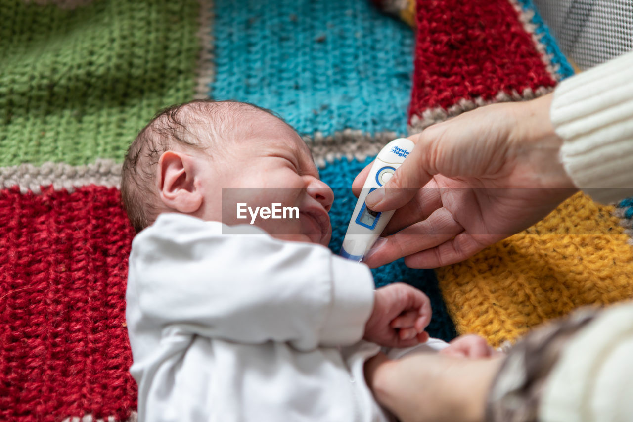 Cropped hand of mother checking temperature of baby