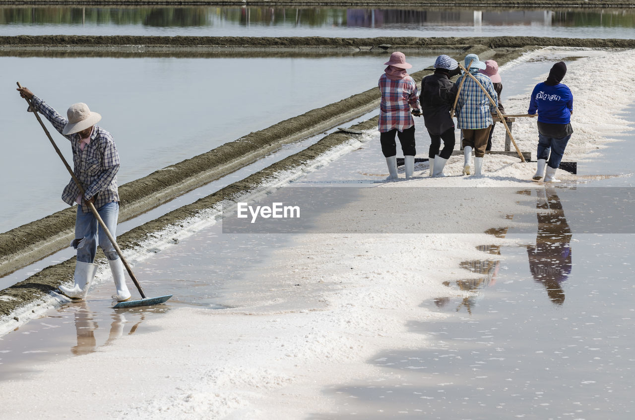 Farmers are using the tools to scoop the salt into a pile in salt garden at phetchaburi, thailand.